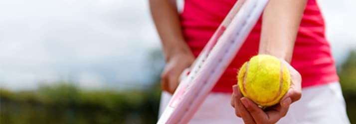 Woman holding tennis ball and racket